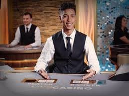 Dealer live casino sedang mengocok kartu untuk permainan baccarat